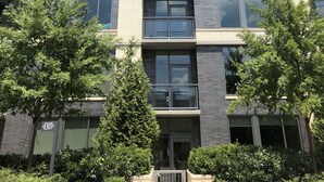 A multi-story building with a modern architectural design, featuring a mix of brick and glass facade, and balconies on each floor. - New World Stay (McLean)
