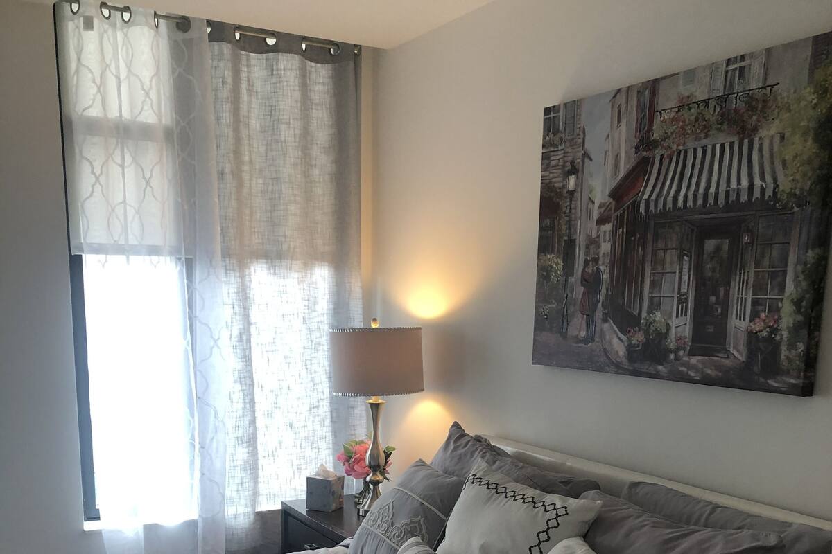 A bedroom with a large bed, a nightstand with a lamp, and a painting on the wall.