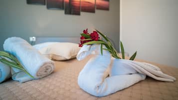Un lit bien fait, avec des serviettes pliées et un joli arrangement floral.