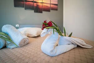 Cama bem arrumada com toalhas dobradas e um arranjo floral decorativo.