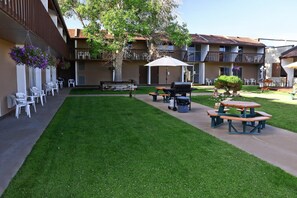 A courtyard with a picnic table, chairs, and a barbecue grill. - Sundowner Station (Riverton)