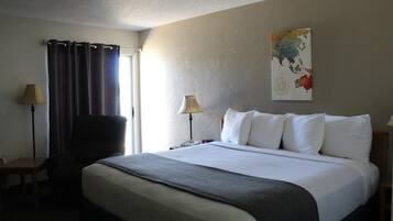Una habitación de hotel con una cama grande, dos lámparas de noche, una silla, una mesita y un mapa en la pared.