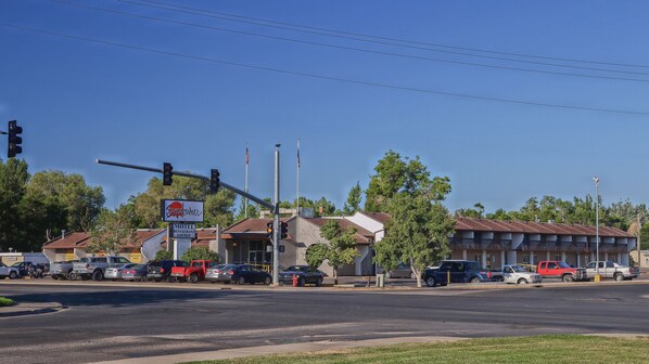 A motel with a restaurant lounge, a red truck, and several cars parked in front. - Sundowner Station (Riverton)