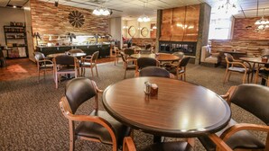 Un restaurant avec des tables et des chaises rondes, un coin bar et un jeu de fléchettes accroché au mur.
