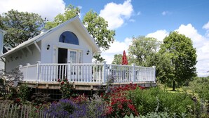 Una casa blanca con balcón, rodeada por un jardín con diversas plantas y flores.