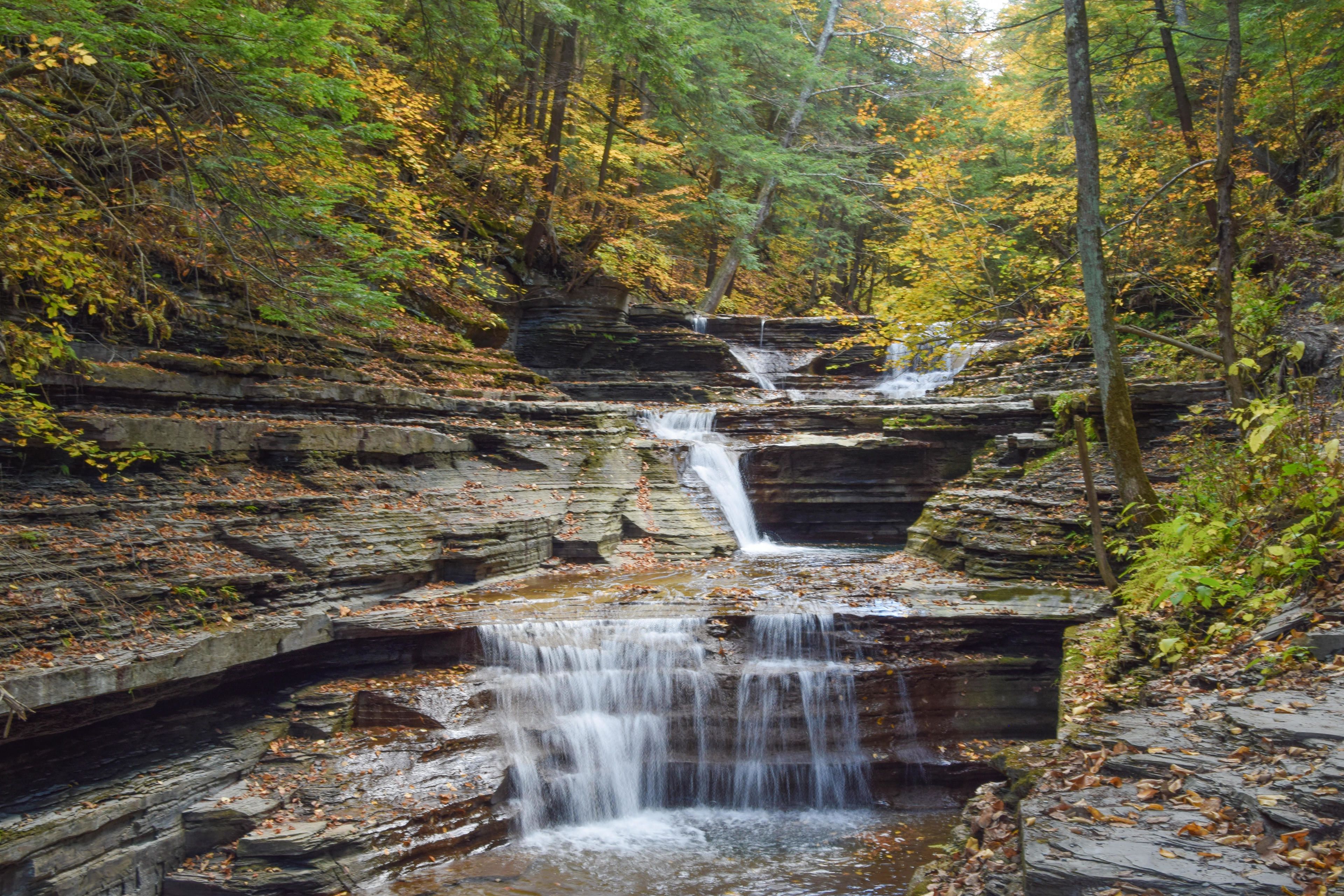 A waterfall cascading over rocky terrain surrounded by autumn foliage.