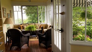 Habitación iluminada por el sol con muebles de mimbre y vista a zonas verdes, además de una puerta con cerradura.