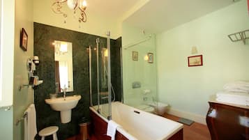 A modern bathroom with a freestanding bathtub, a glass-enclosed shower, and a marble wall.