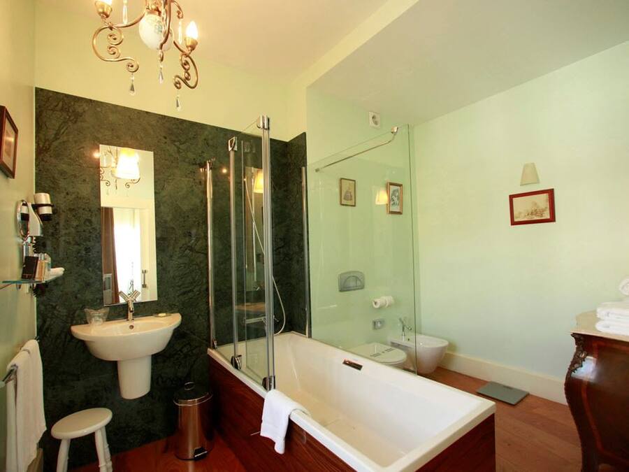 Un baño moderno con una bañera independiente, ducha con mampara de vidrio y pared de mármol.