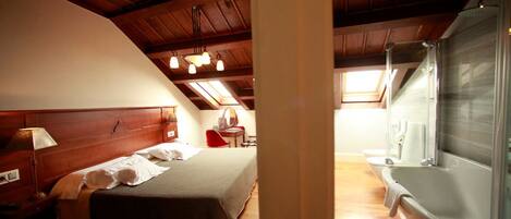 A bedroom with a wooden ceiling, a bed, a nightstand, a desk, a chair, and a bathtub.