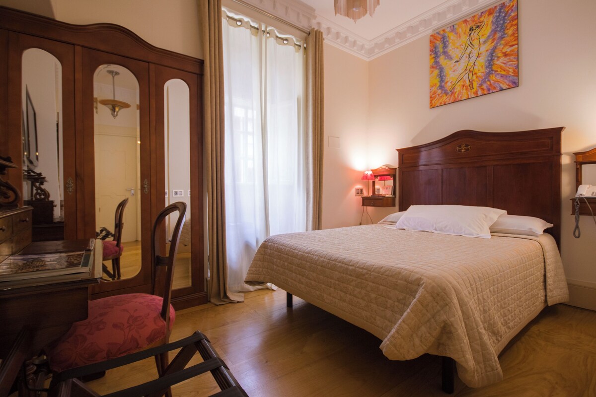 Ein Schlafzimmer mit einem Bett, einem Schreibtisch, einem Stuhl, einem Kleiderschrank und einem Bild an der Wand.