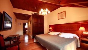A bedroom with a wooden headboard, a bed with white linens, a wooden nightstand with a lamp, and a wooden wardrobe.