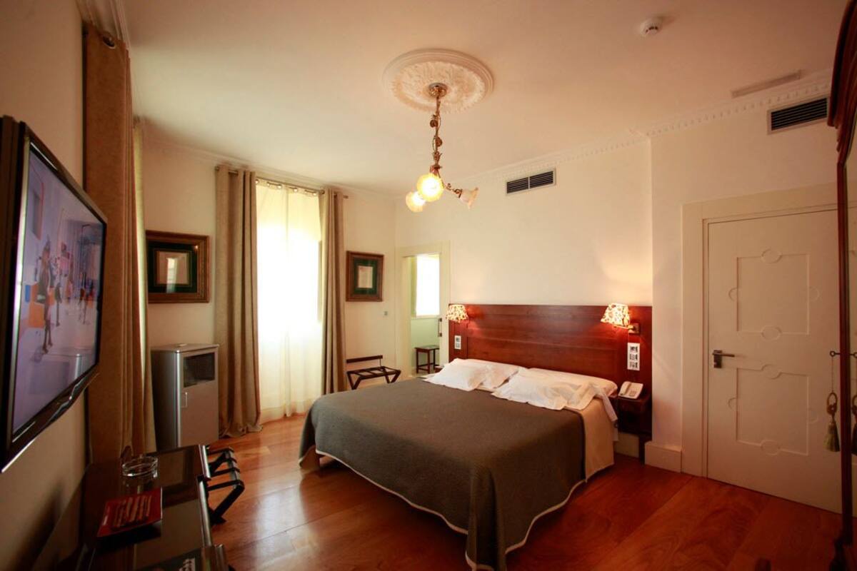 Ein Hotelzimmer mit Bett, Fernseher, Schreibtisch und Tür.