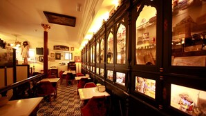 Un restaurant avec un long comptoir, des chaises rouges et un sol à motifs.