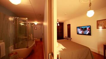 Una habitación de hotel con bañera, televisor y cama.