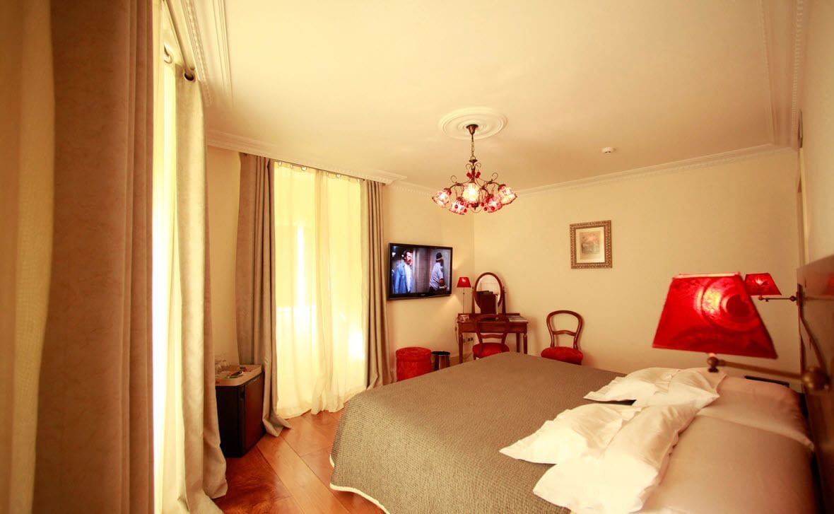 Una habitación de hotel con una cama, televisión, escritorio y silla.