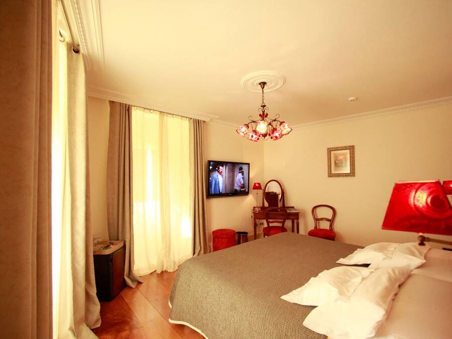 A hotel room with a bed, a television, a desk, and a chair.