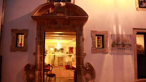 Une entrée surmontée d’une arche en pierre qui mène à un intérieur chaleureux et bien éclairé.