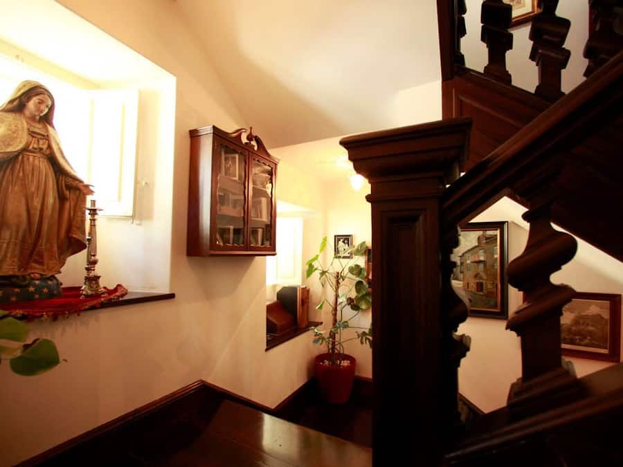 Un escalier avec des balustrades en bois et un pot de fleurs placé à côté.