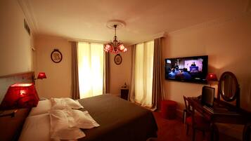 Een hotelkamer met een bed, een televisie, een bureau met een stoel en een rode lamp.