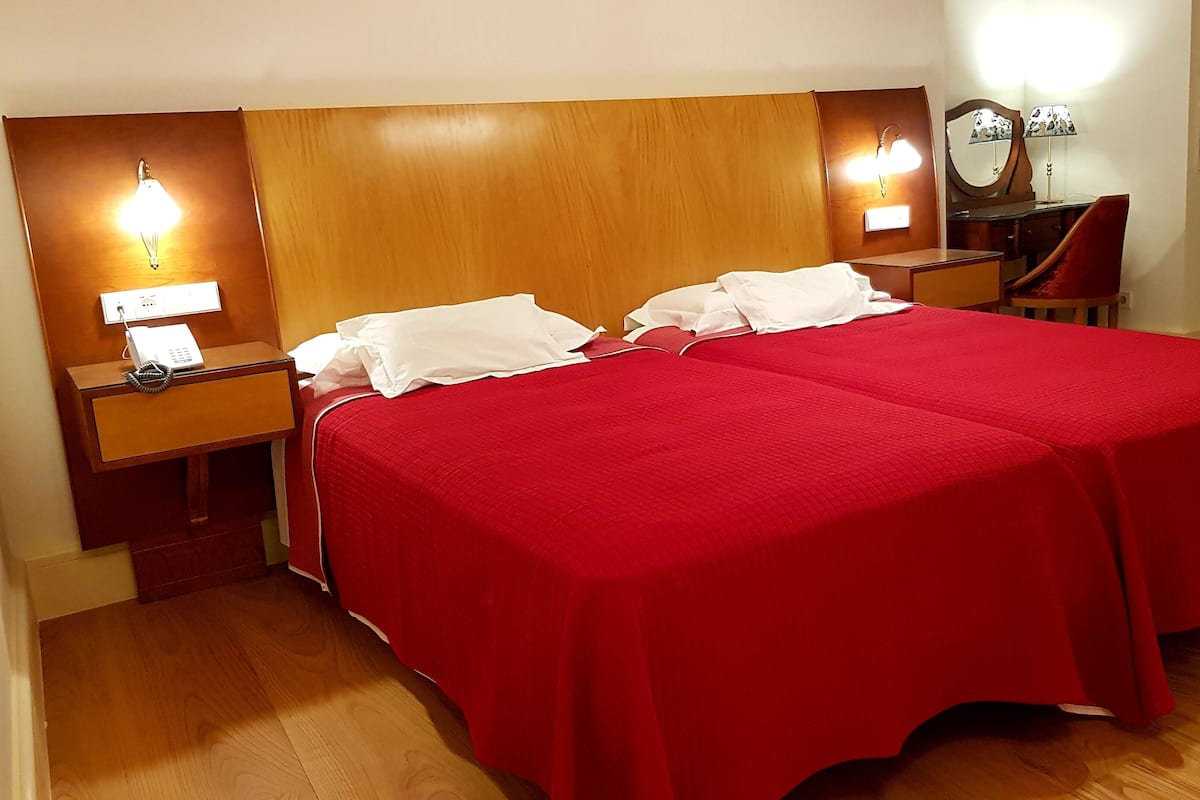 Ein Hotelzimmer mit einem großen Bett, zwei Nachttischen, einem Telefon und einem Spiegel.