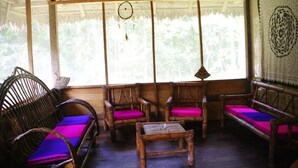 Una habitación con muebles de madera, incluyendo un sofá y sillas con cojines morados, y una pequeña mesa.