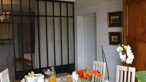 Un coin repas avec une table mise pour le petit-déjeuner, comprenant des assiettes, des tasses et un vase avec des fleurs.