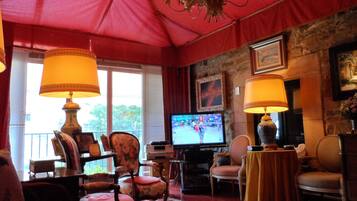 Een gezellige woonkamer met een televisie, comfortabele zitplaatsen en een rode paraplu erboven.