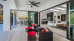 Un salon moderne doté d’une porte vitrée donnant sur un coin repas, d’un ventilateur de plafond et d’une grande fenêtre.