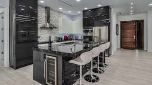 Une cuisine moderne dotée d’un îlot central, d’appareils électroménagers en acier inoxydable et de tabourets de bar.