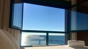 Een kamer met een groot raam en uitzicht op de zee.