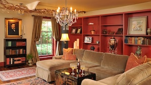A cozy living room with a sectional sofa, a coffee table, and a bookshelf filled with books. - 1795 Acorn Inn B&B (Canandaigua)