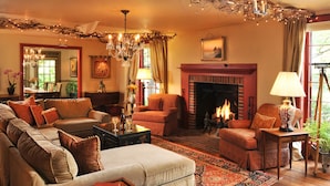 A cozy living room with a fireplace, comfortable seating, and a chandelier. - 1795 Acorn Inn B&B (Canandaigua)