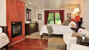 A bedroom with a fireplace, a bed, a dresser, and a nightstand with lamps. - 1795 Acorn Inn B&B (Canandaigua)