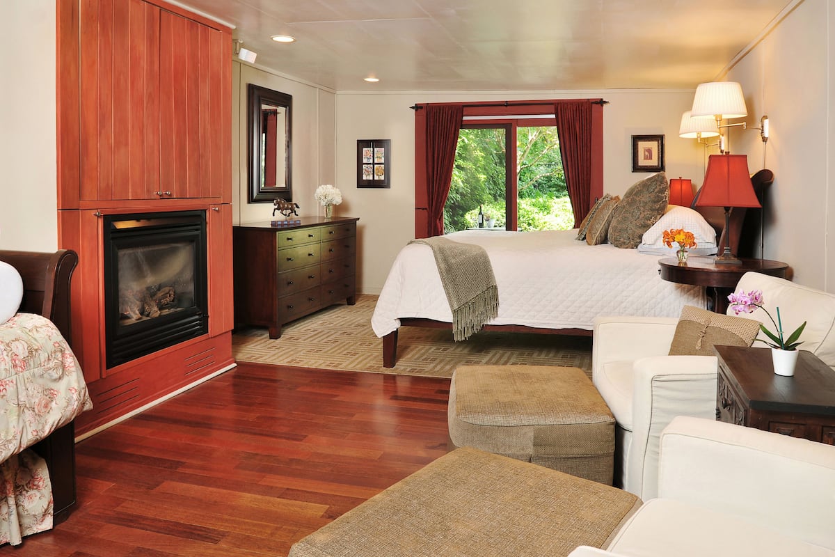 A bedroom with a fireplace, a bed, a dresser, and a nightstand with lamps.