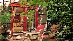 A cozy outdoor seating area with wicker furniture, a table, and a potted plant. - 1795 Acorn Inn B&B (Canandaigua)