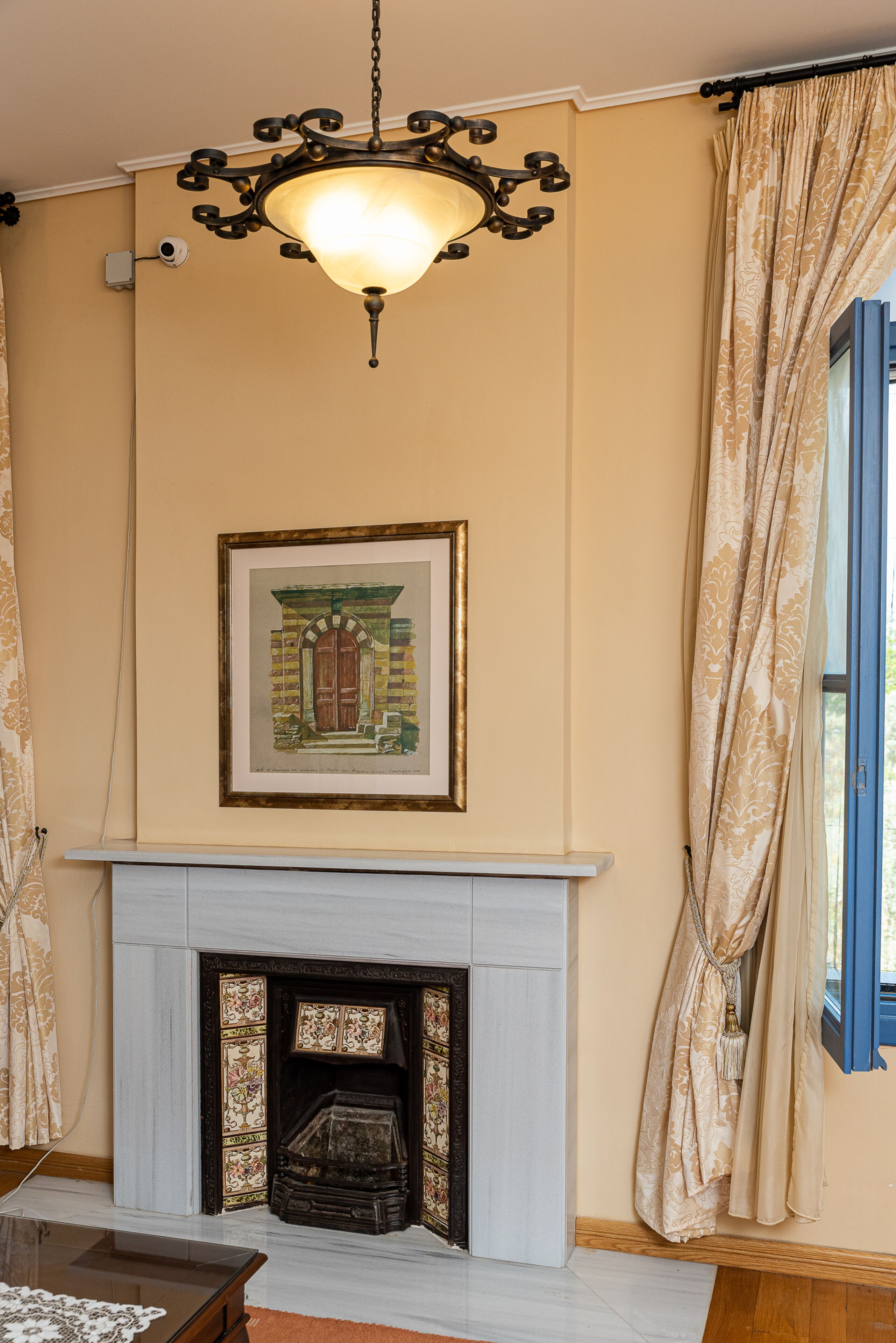 Una habitación con chimenea, un cuadro en la pared y una lámpara colgante.