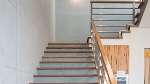 A modern staircase with wooden steps and metal railings, leading to a landing with a refrigerator and a wooden panel wall. - Here is BNB (Zhongpu)