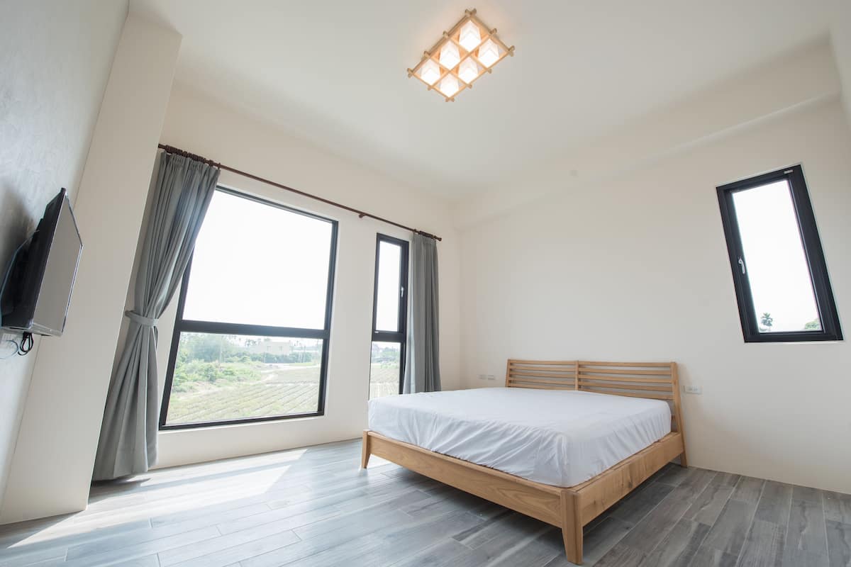 Un dormitorio con un ventanal grande, una cama y una lámpara en el techo.