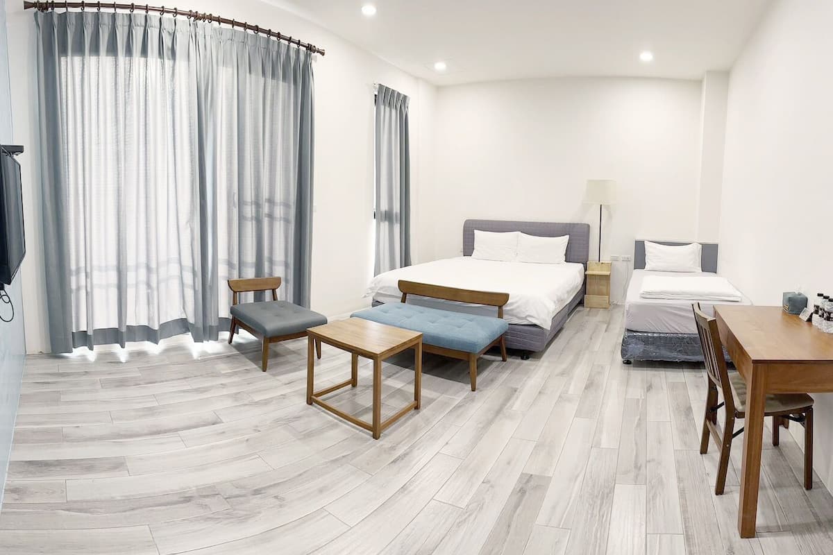 Habitación de hotel con cama, escritorio, silla, mesita y sofá.