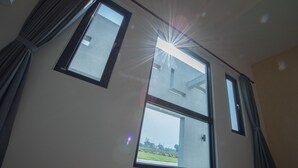 A room with two windows, one of which has a view of a building and a grassy area outside. - Here is BNB (Zhongpu)