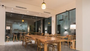 A spacious meeting room with a long wooden table and chairs, large windows, and modern lighting fixtures. - Here is BNB (Zhongpu)