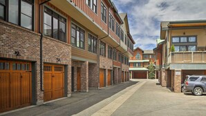 A row of brick buildings with wooden garage doors, a clear sky, and a parked car. - Elegant Frisco Condo w/ Private Hot Tub & Views! (Frisco)
