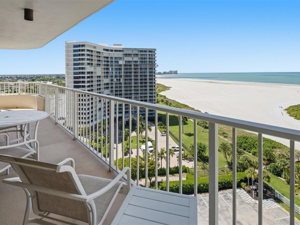 A balcony with a view of a beach and a high-rise building.