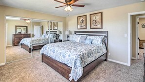 A bedroom with a large bed, a ceiling fan, and a mirror. - Lake Havasu Home w/ Pool, Near London Bridge! (Lake Havasu City)