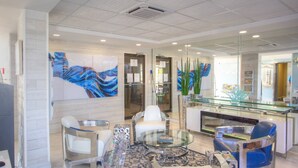 A modern lobby with a glass reception desk, white leather chairs, and abstract art on the walls.