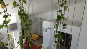Un interior moderno con una escalera de madera, paredes blancas y plantas verdes.