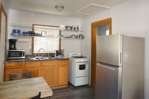A kitchen with wooden cabinets, a gas stove, a microwave, and a refrigerator.