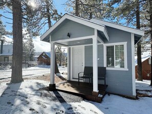 A small cabin with a porch, a door, and a window.