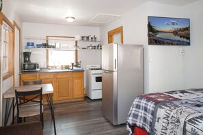 A compact kitchen with a refrigerator, stove, microwave, and wooden cabinets.